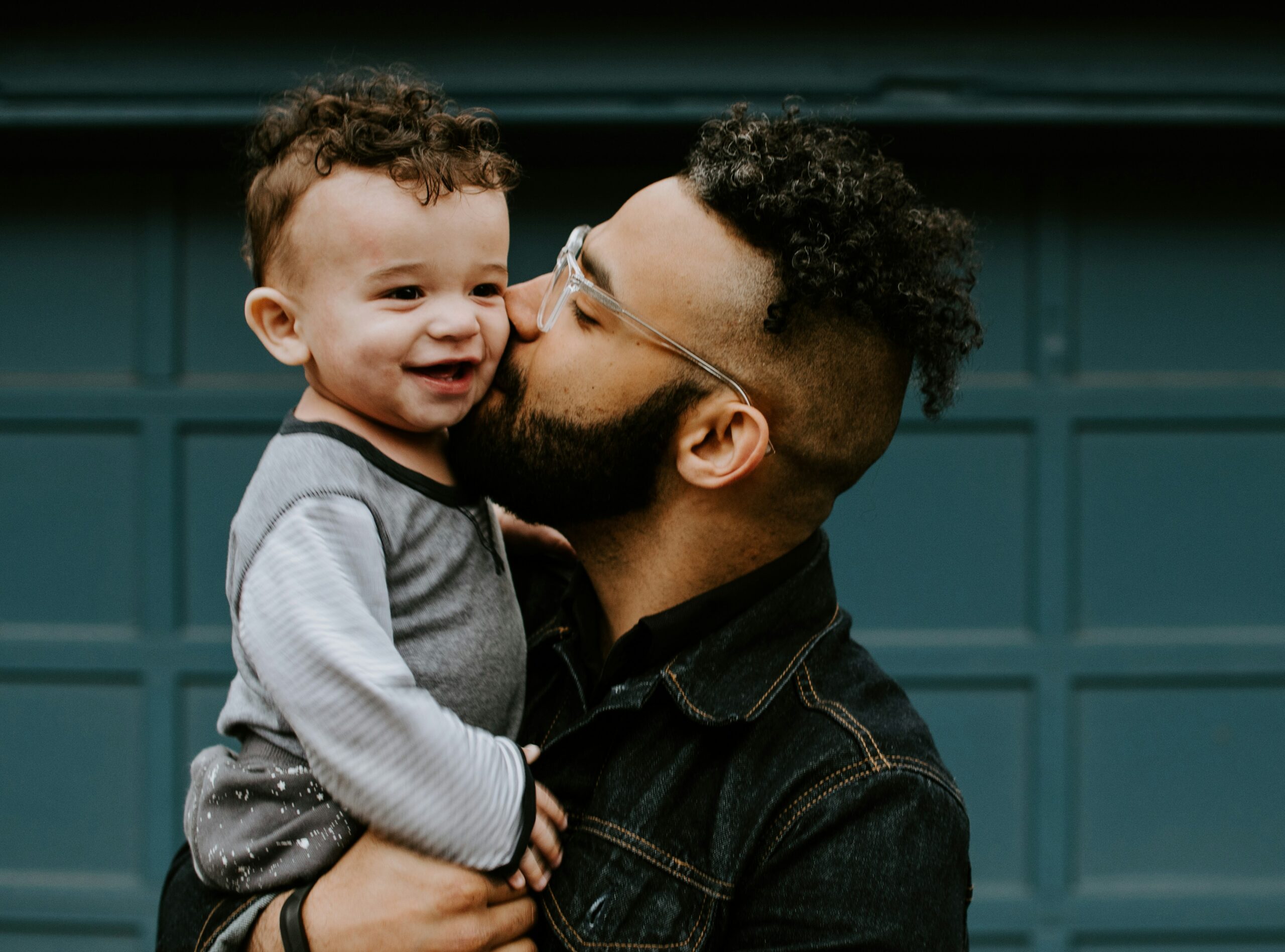Padre abrazando y besando a su hijo pequeño al aire libre